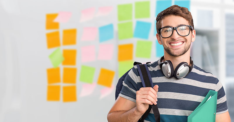 Executive in spectacle holding backpack standing in the office
